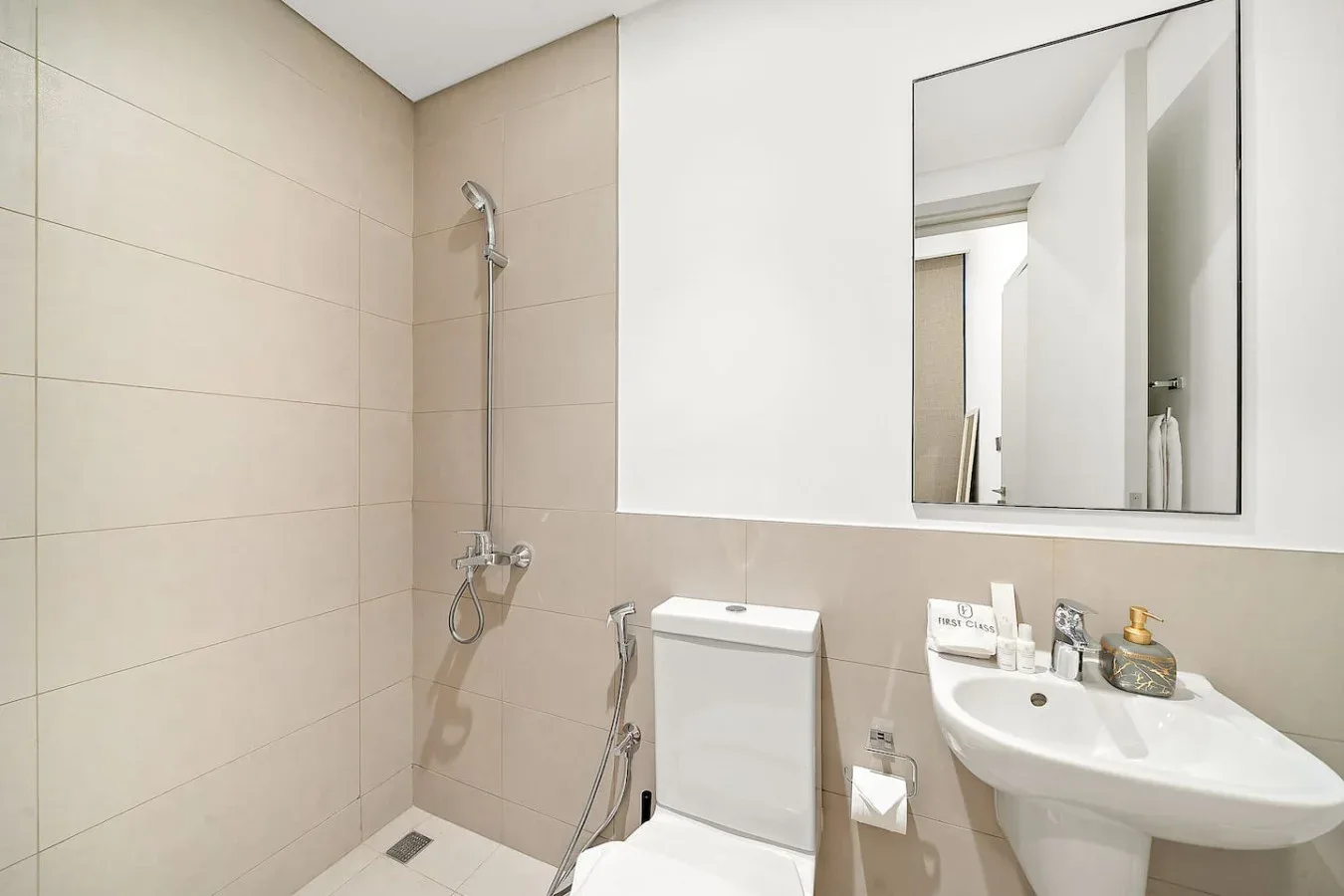 Un baño con ducha de pared, inodoro y lavabo.