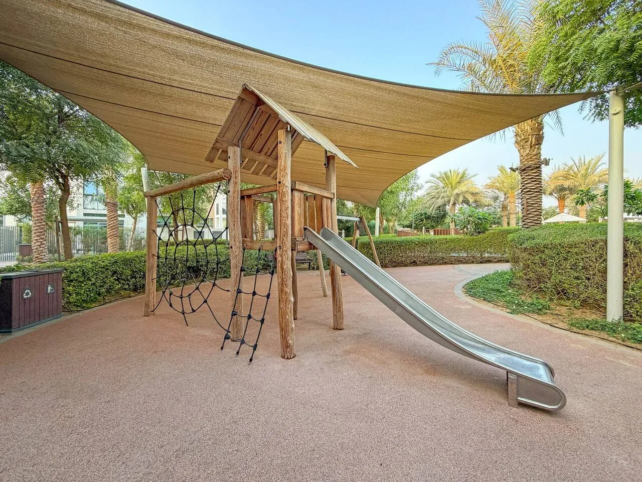 Un parque infantil al aire libre cuenta con una estructura de madera para trepar y un tobogán.