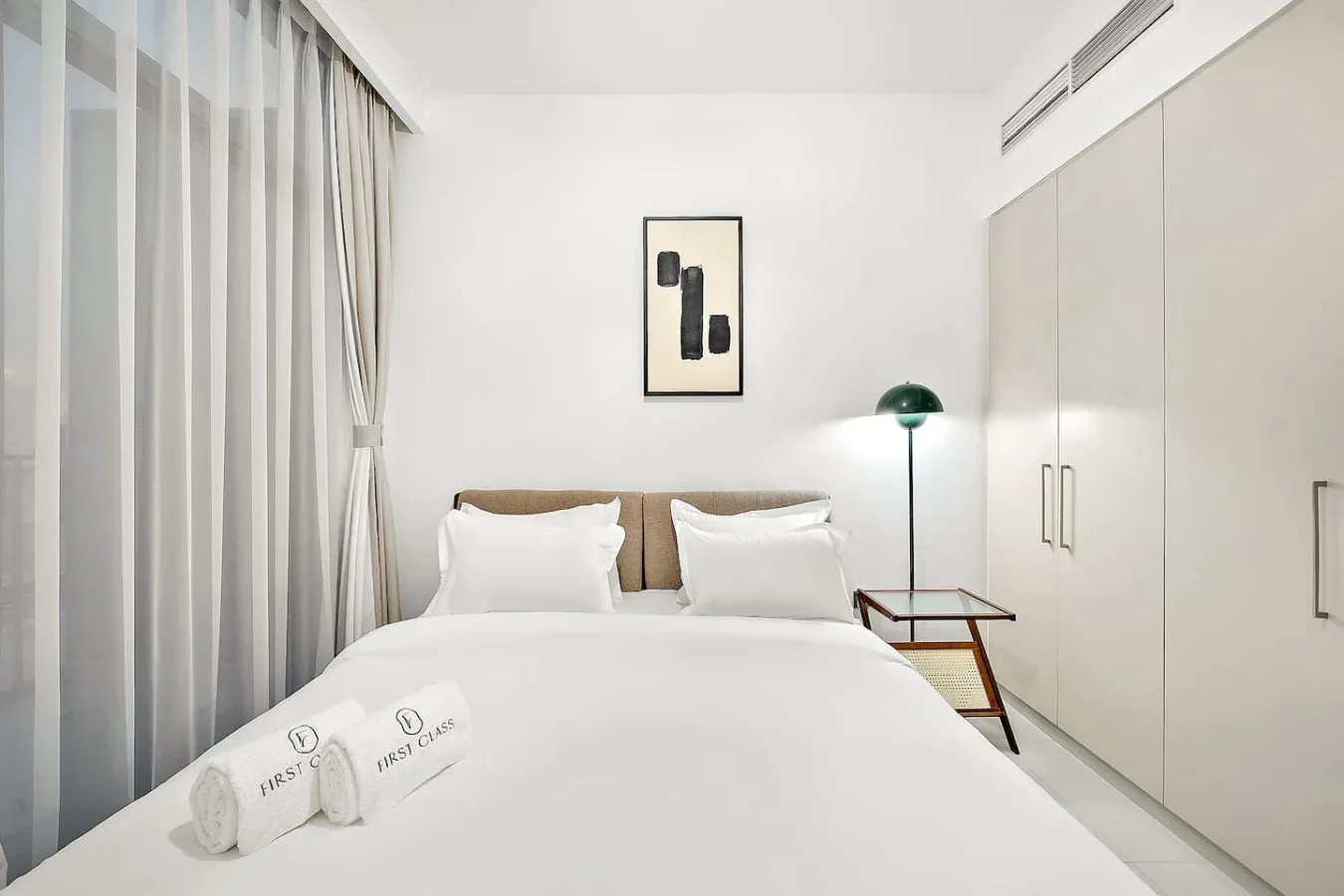 Un dormitorio luminoso con una cama bien hecha y cortinas de cuerpo entero.