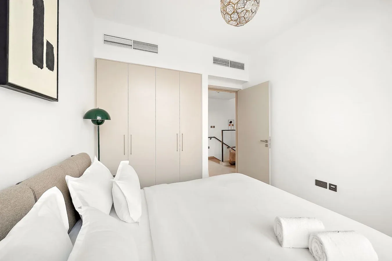 Un dormitorio luminoso con una cama, ropa de cama blanca y armarios empotrados.