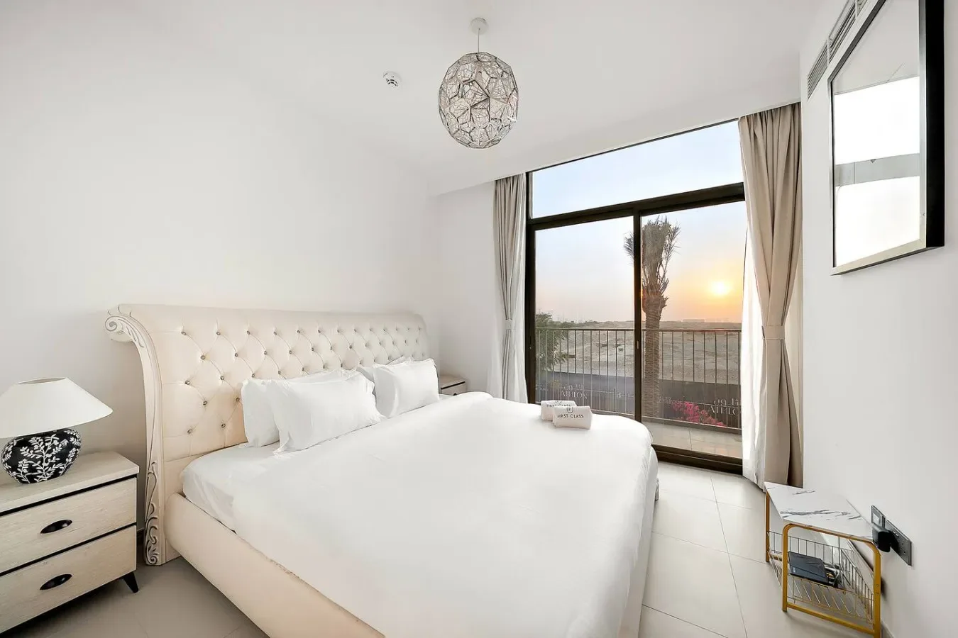 Un dormitorio luminoso con una cama blanca junto a una ventana amplia.