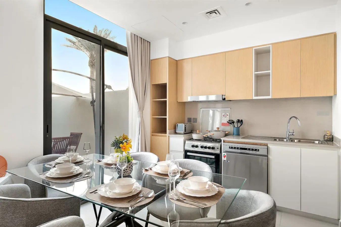 Un comedor con una mesa de vidrio junto a una cocina abierta.