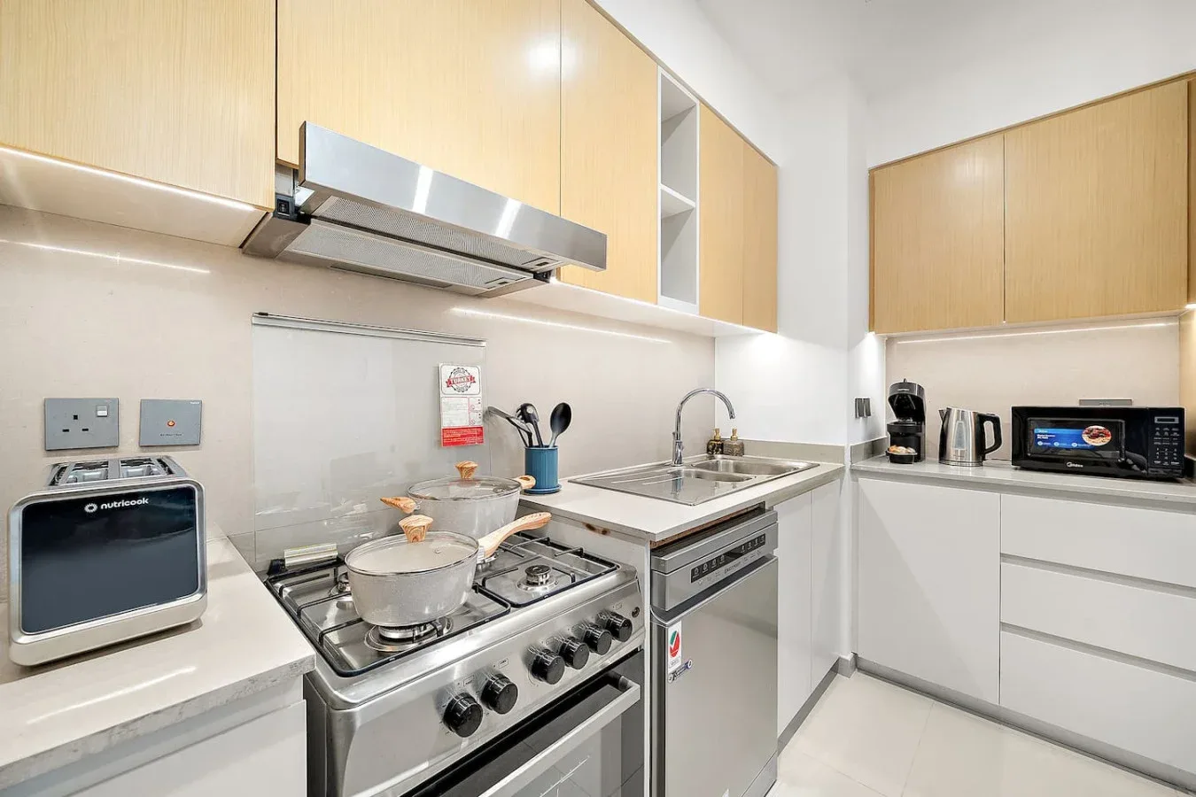 Una cocina luminosa con estufa, fregadero y gabinetes de madera clara.