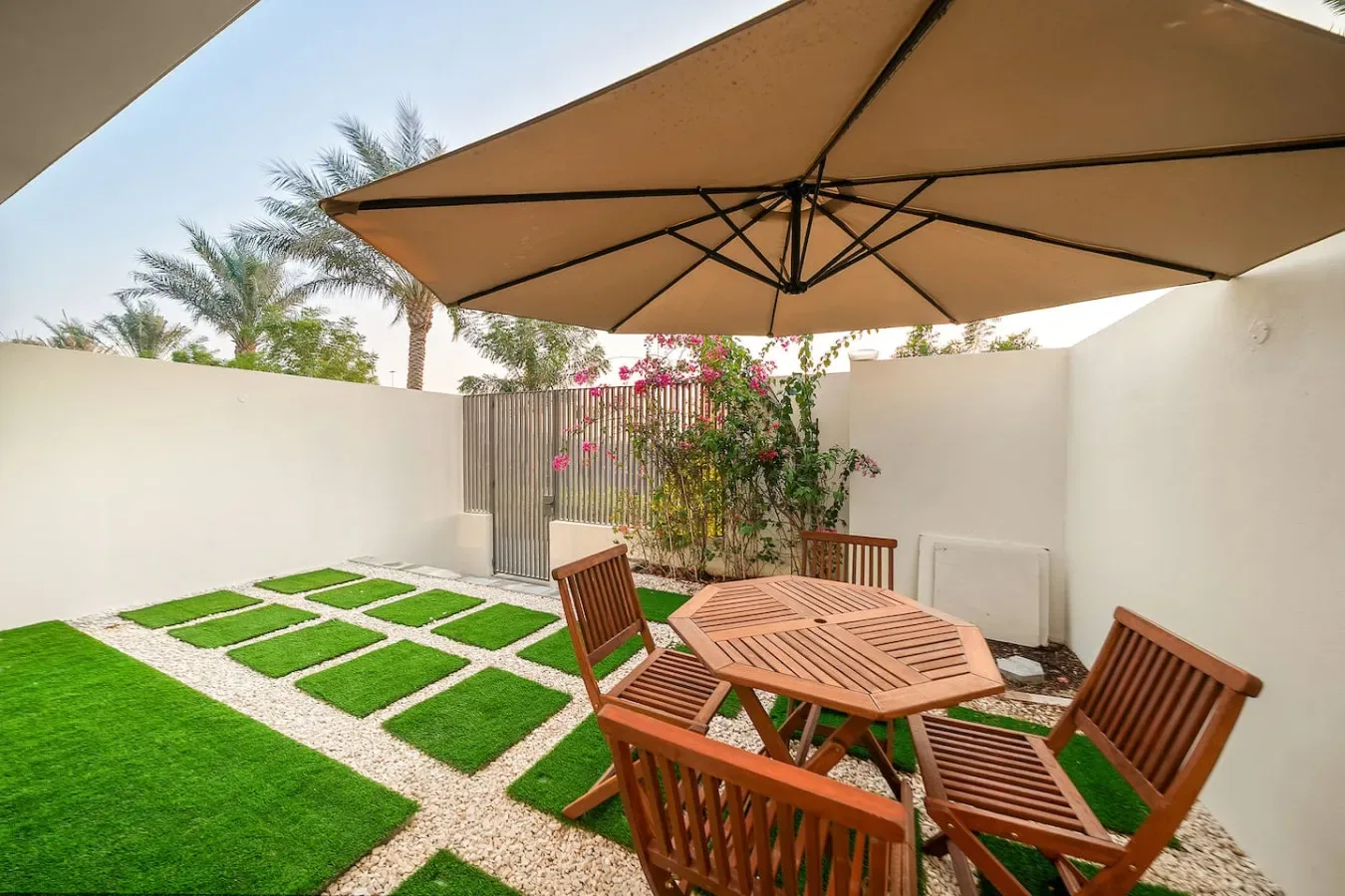 Un patio al aire libre con asientos de madera bajo una gran sombrilla.