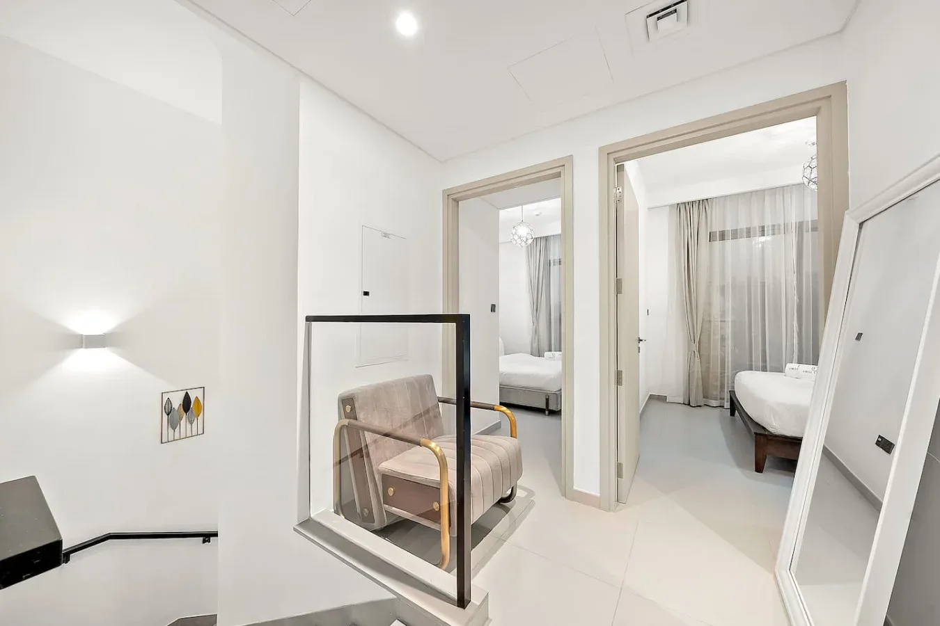 Un interior blanco y luminoso con una pequeña zona de estar junto a dos puertas abiertas.