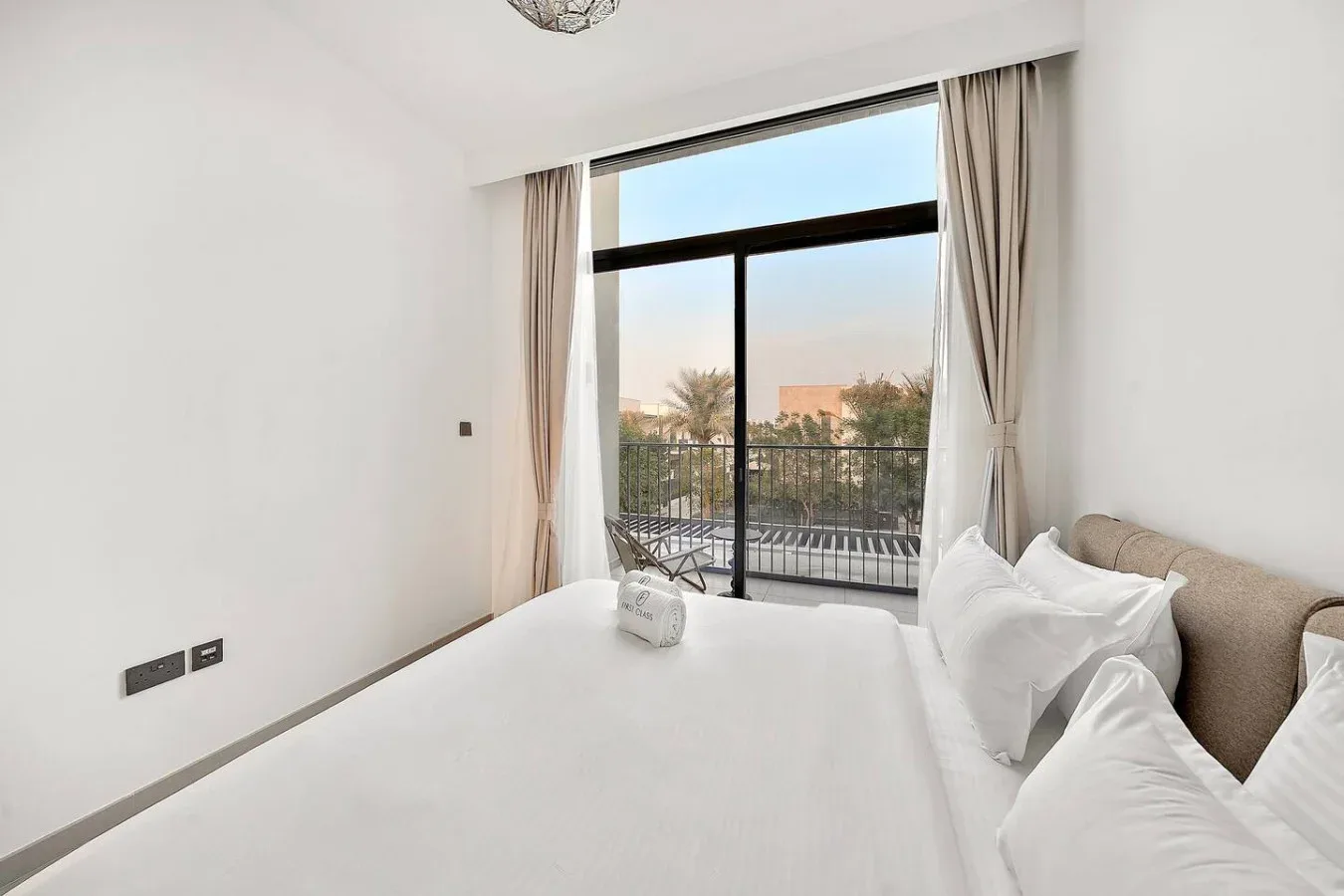 Un dormitorio luminoso con una ventana grande y cortinas junto a la cama.