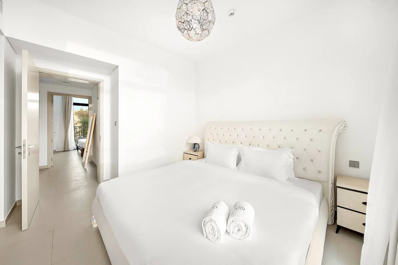 Un dormitorio luminoso con una cama grande y una puerta que da a un pasillo.