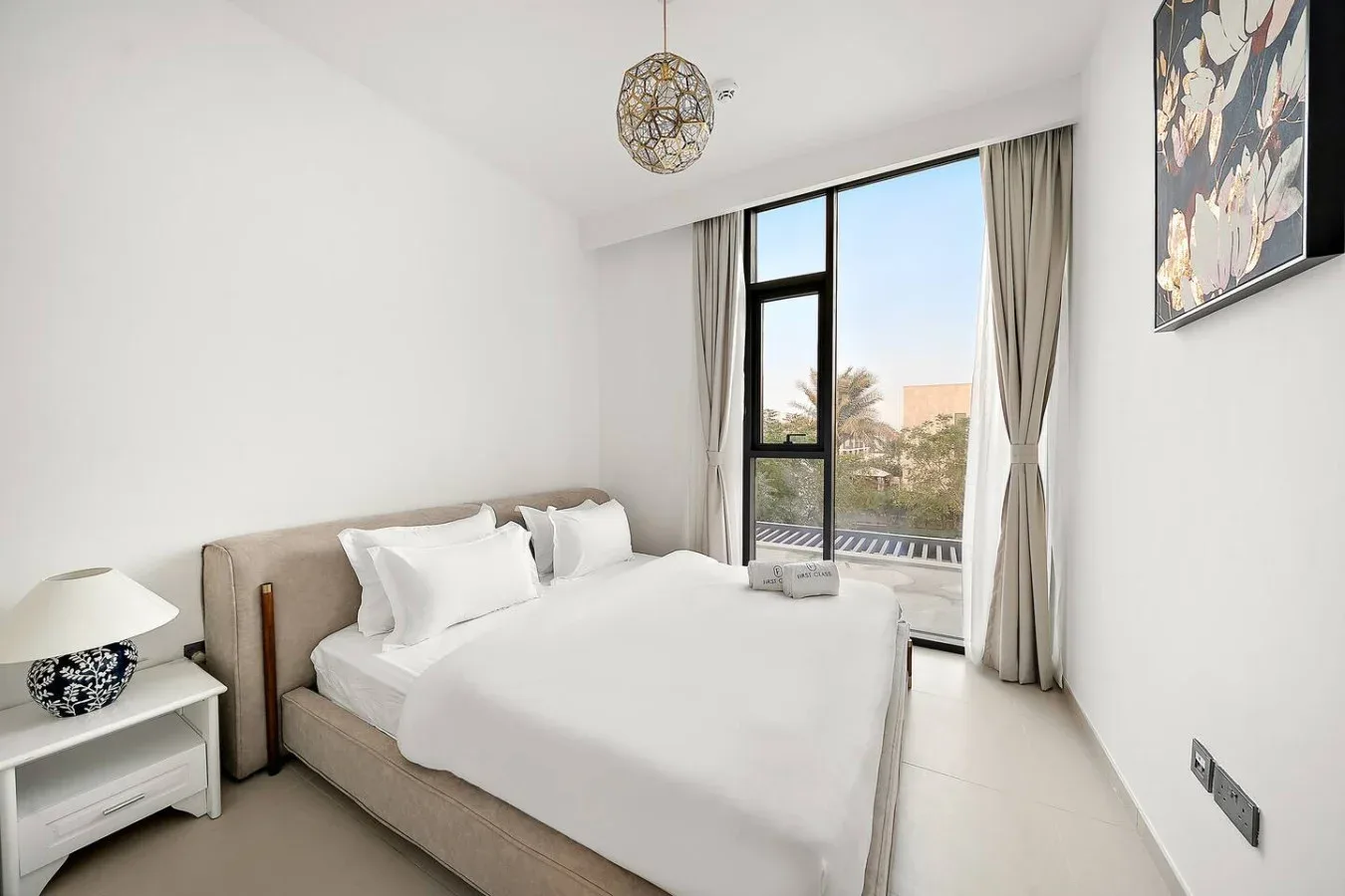 Un dormitorio luminoso con una cama tendida junto a una ventana alta.
