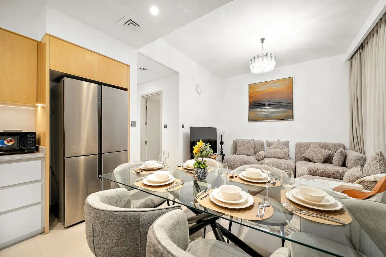 Comedor con mesa de cristal y asientos, junto a una zona de estar.