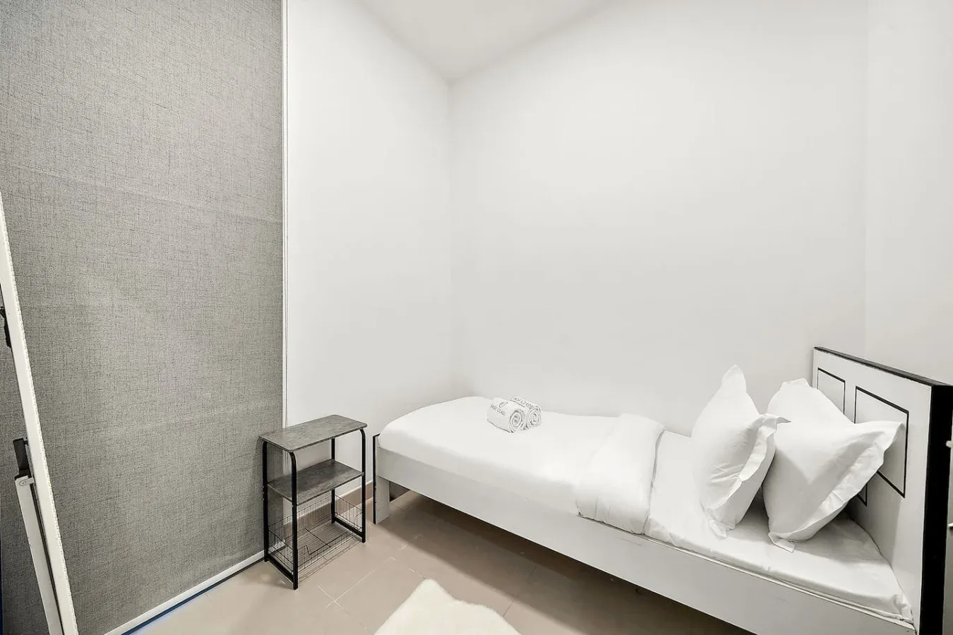 Un dormitorio luminoso con una cama individual y una mesita de noche.