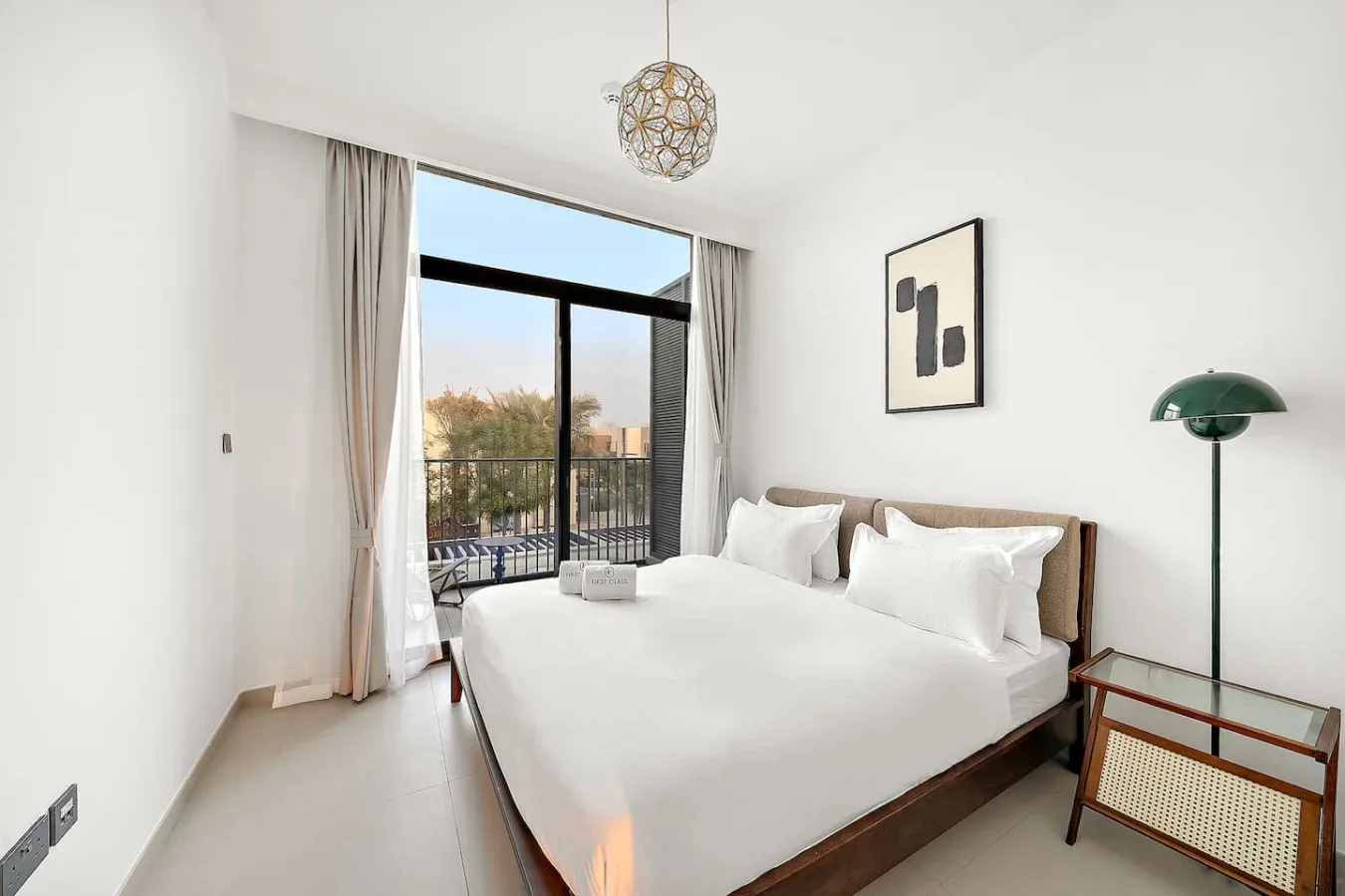 Un dormitorio luminoso con una cama bien arreglada junto a una ventana grande.