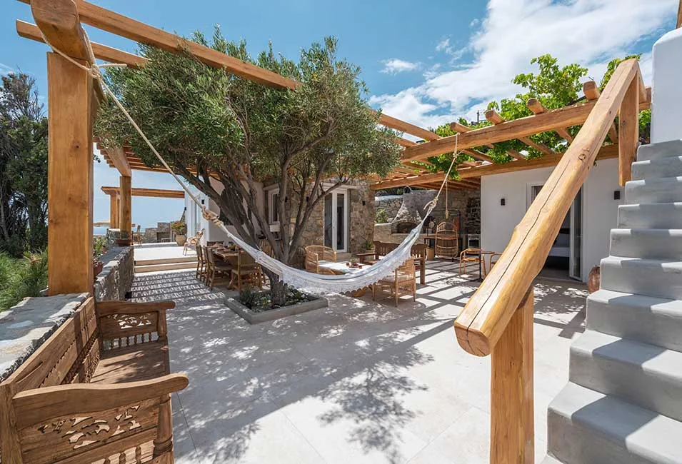 A shaded outdoor patio with a hammock beneath a wooden pergola.