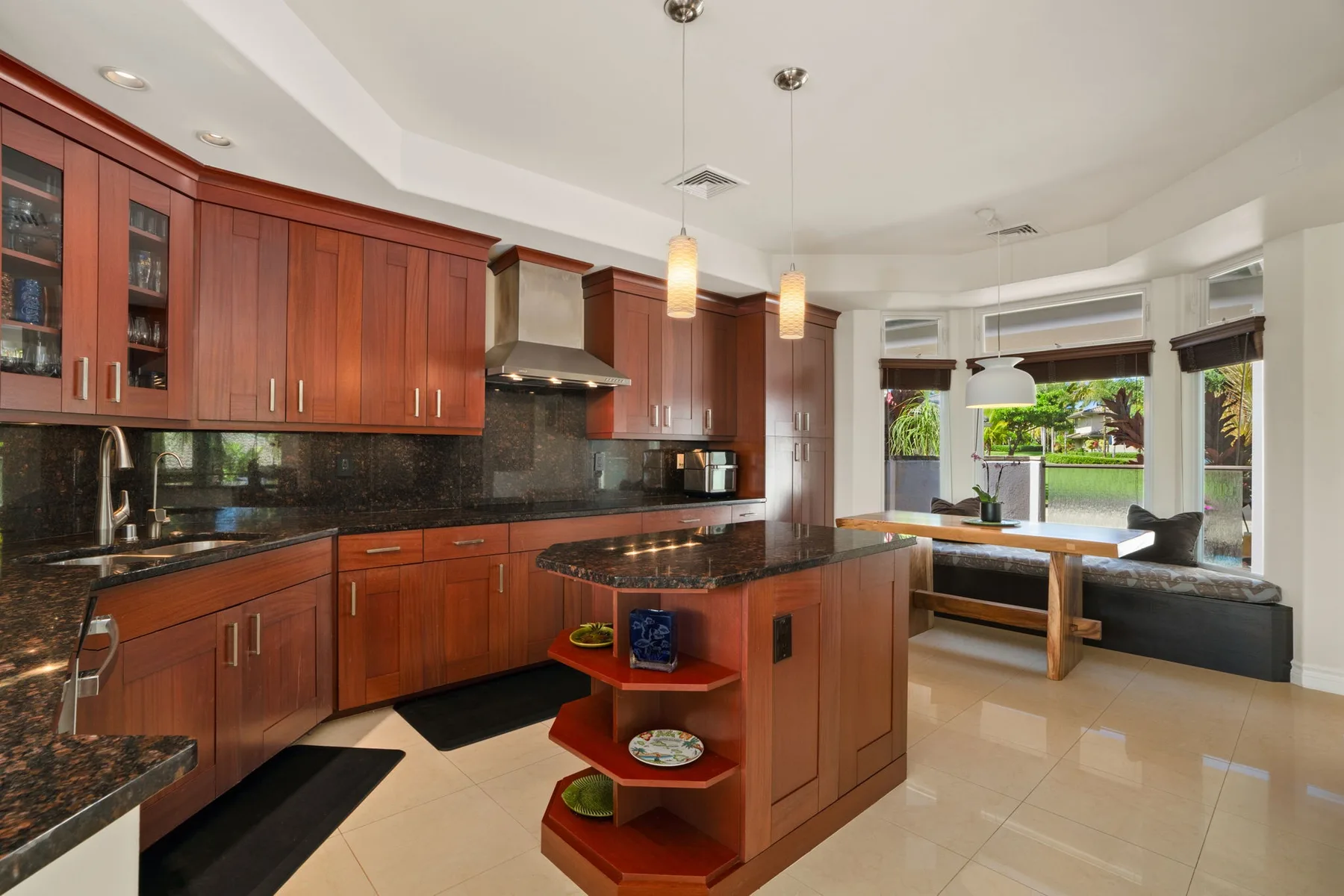 A spacious kitchen with reddish wood cabinets, dark countertops, and a central island.