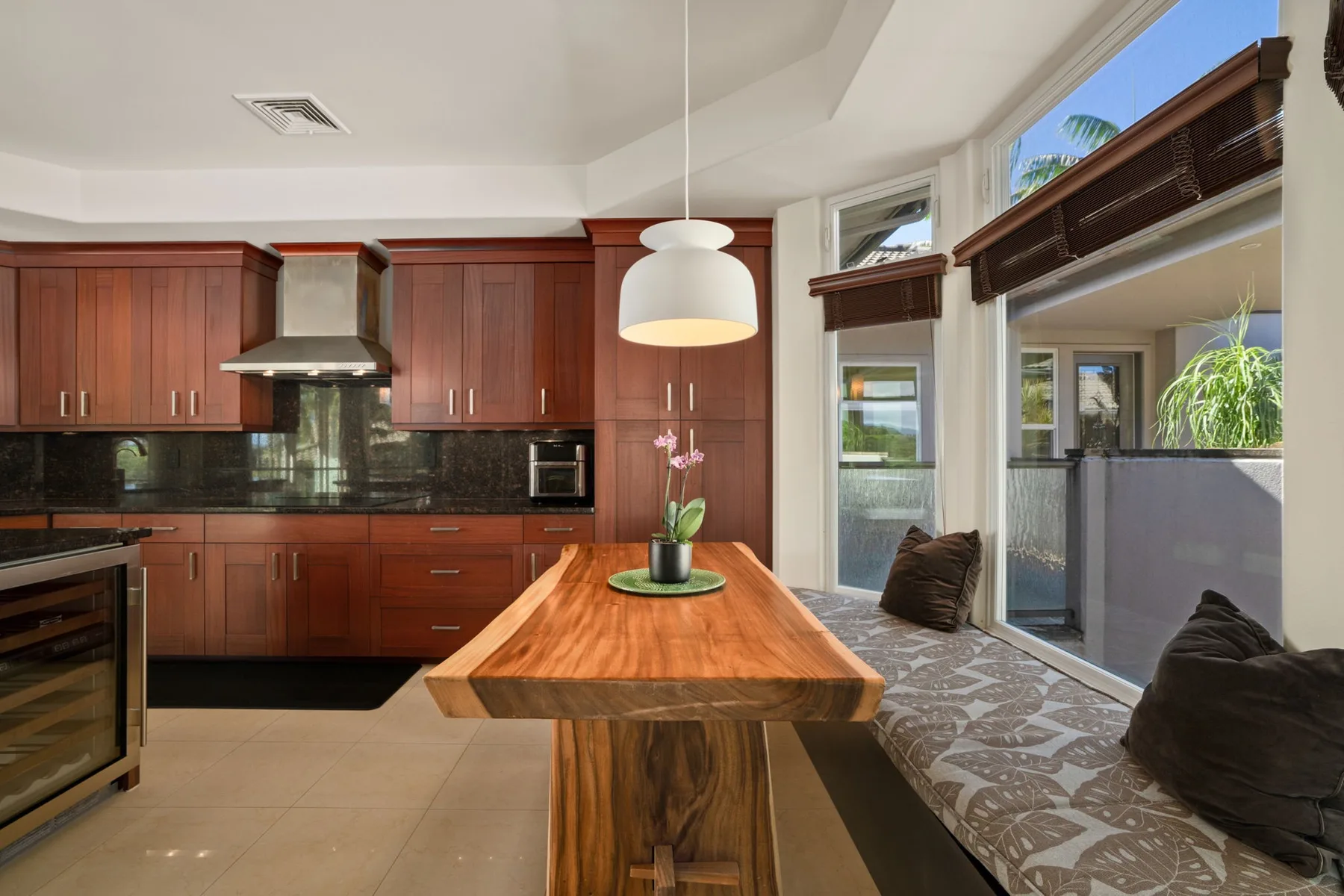 A kitchen with dark wood cabinets opens onto a bright window-side seating area.