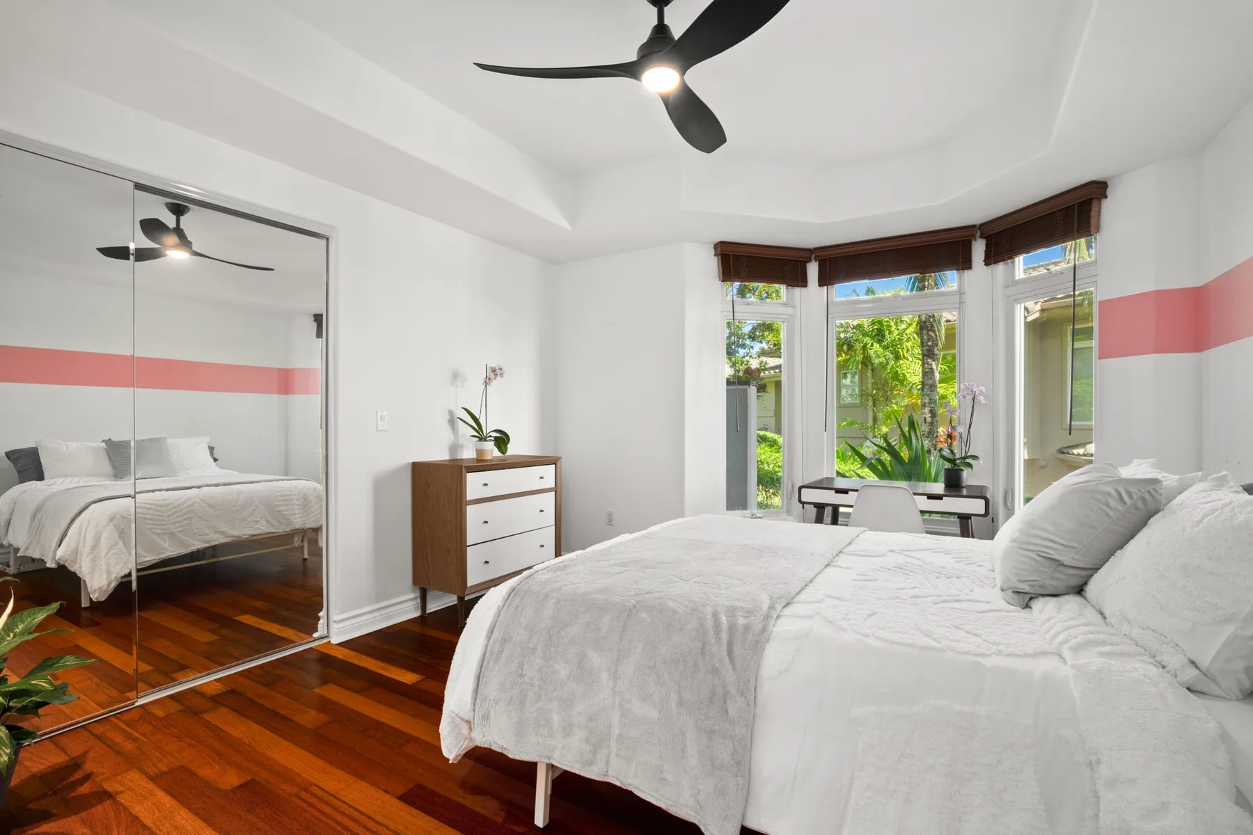 A bright bedroom with a large bed and mirrored closet doors.
