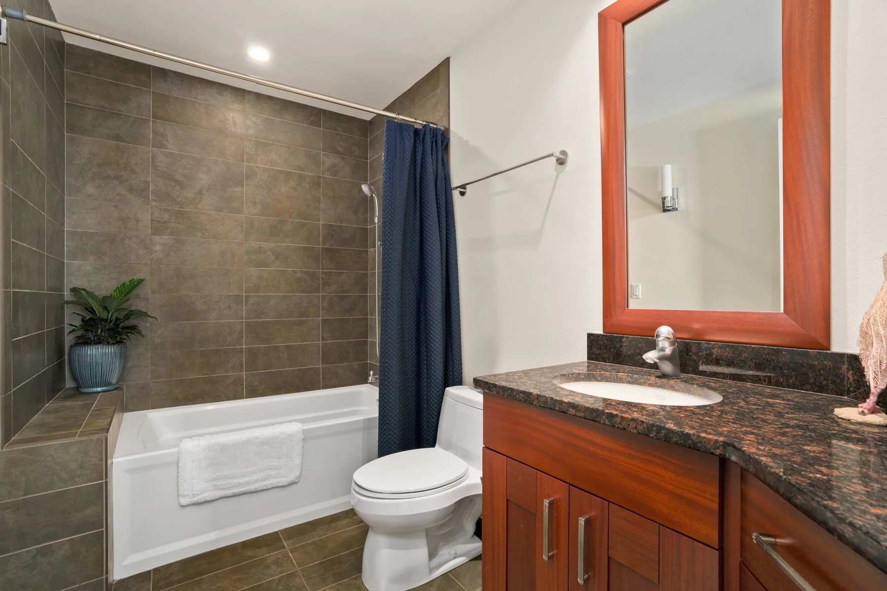 A bathroom with a bathtub, shower curtain, toilet, and vanity.