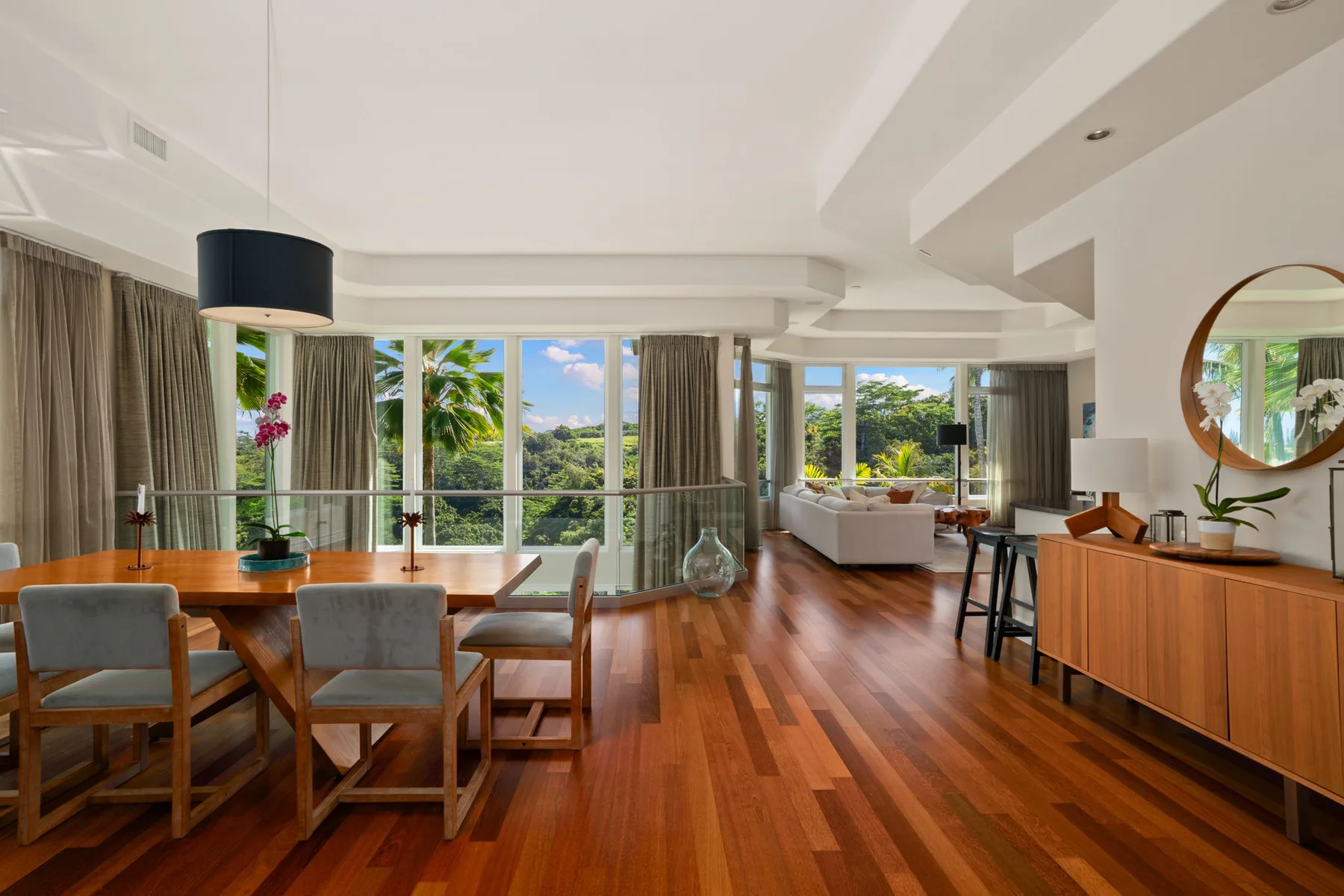 A bright open-plan living and dining area with large windows and wooden flooring.