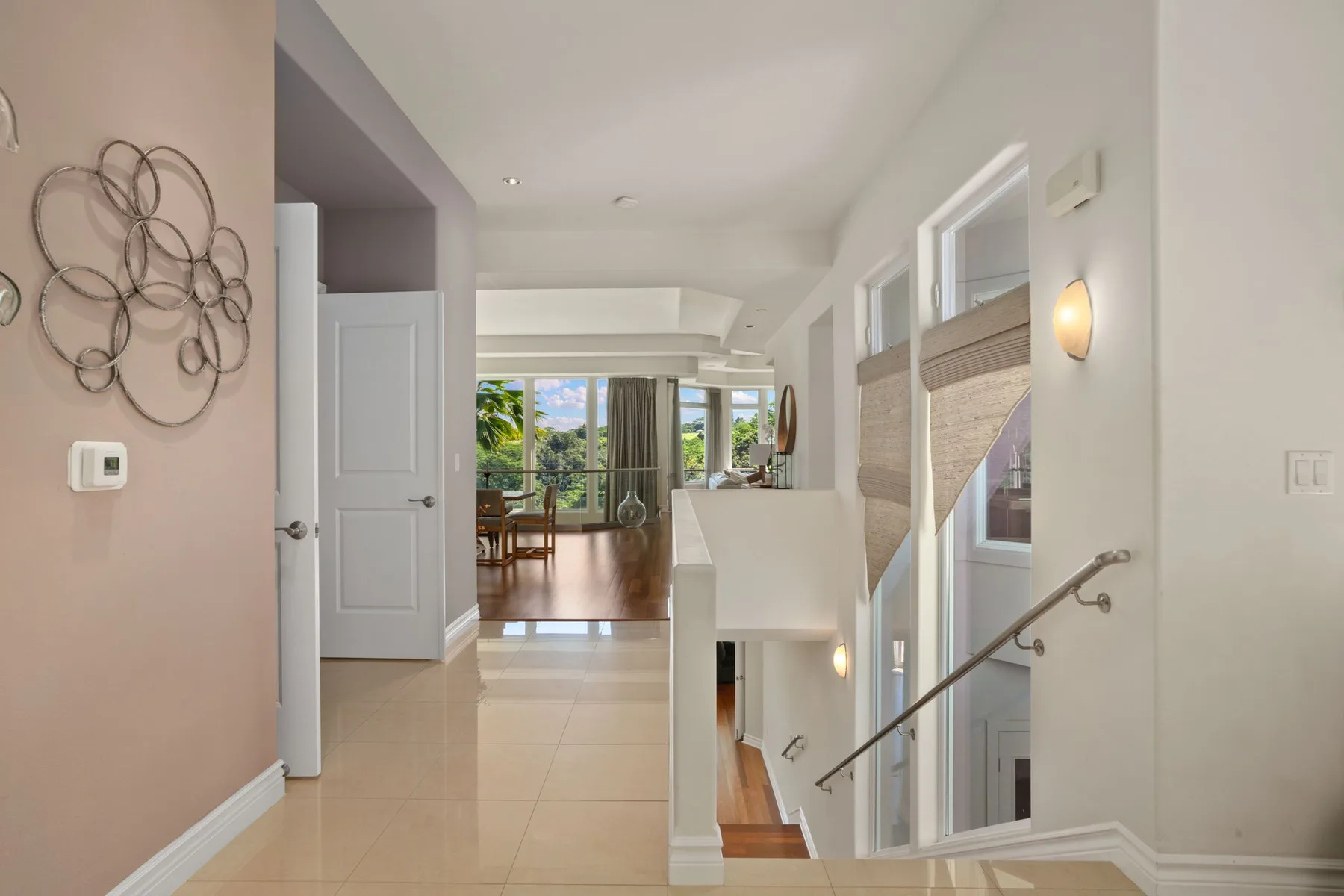 A bright hallway opens toward a dining area, with a staircase along the side.