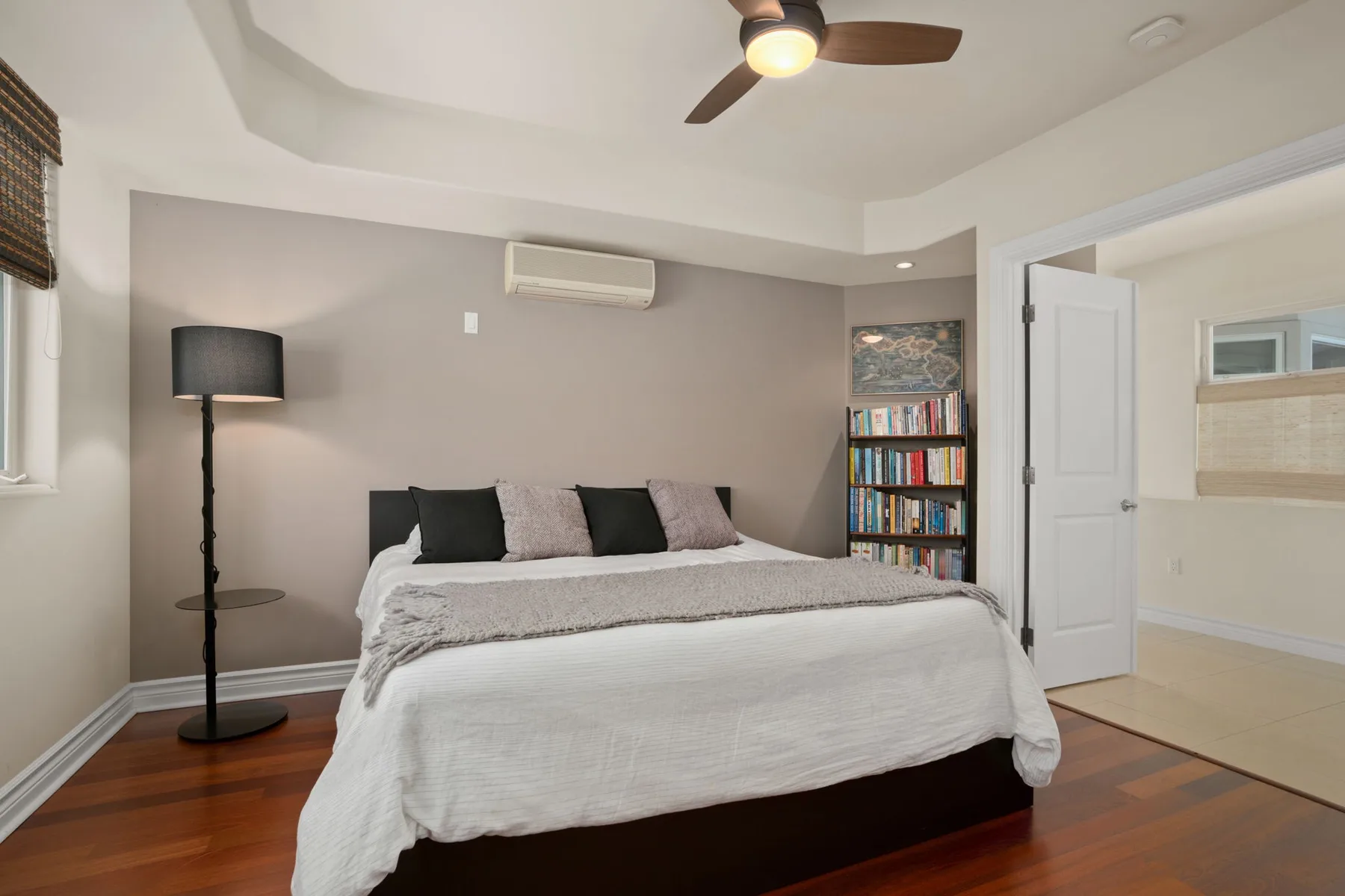 A bedroom with a bed, floor lamp, and bookshelf.