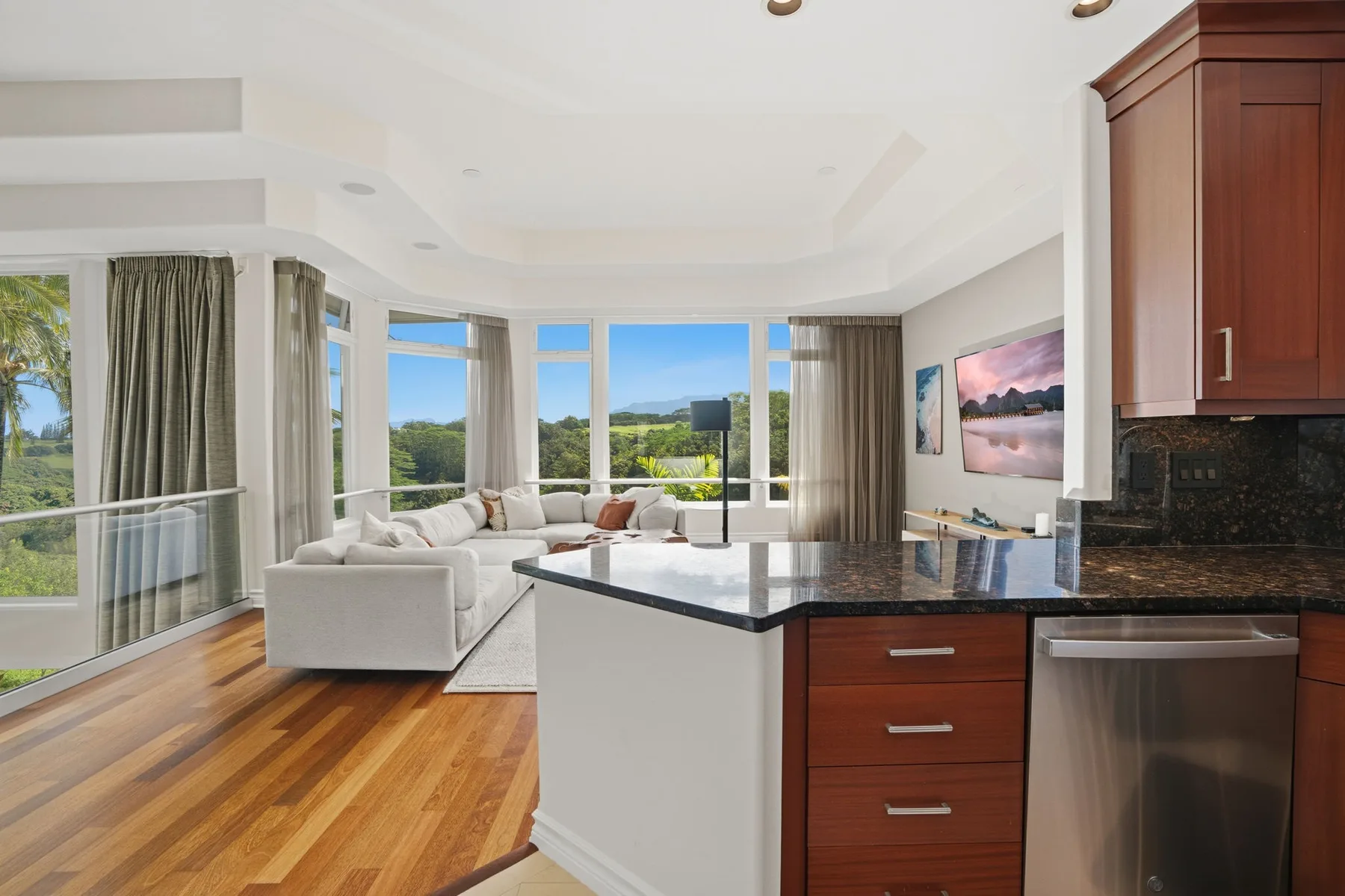 A bright open-plan living room and kitchen with large windows and a seating area.