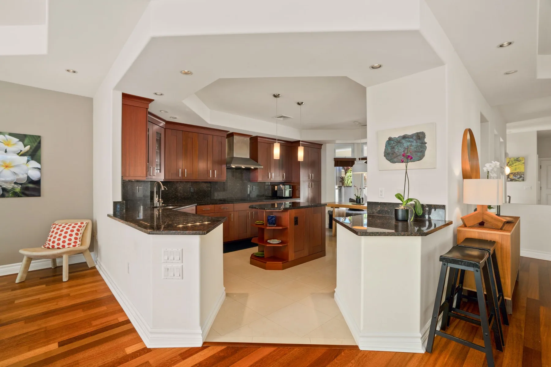 A spacious kitchen with dark wood cabinets, stone countertops, and a central island.
