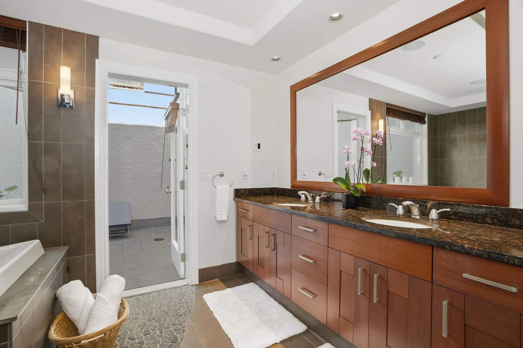 A bathroom with a long vanity, large mirror, and an open shower area.