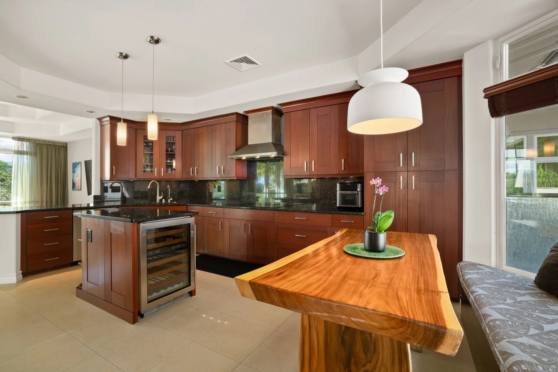 A modern kitchen with dark wood cabinets, an island, and a wooden dining table.