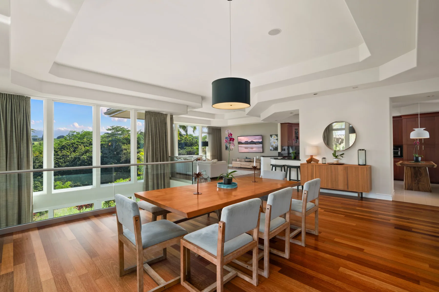 A bright dining and living area with large windows and a wooden dining table.