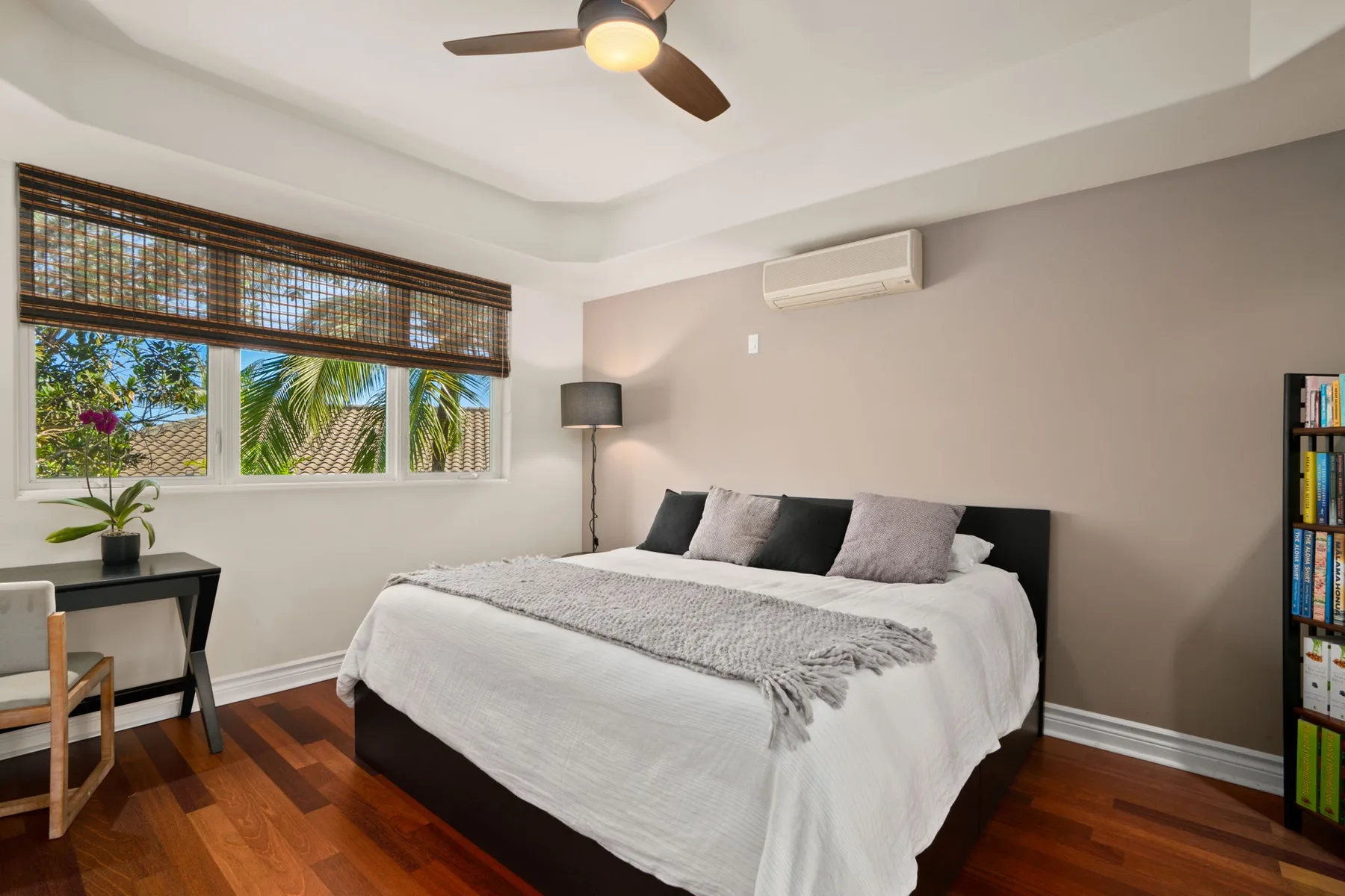 A bedroom with a bed, wide windows, and a ceiling fan.
