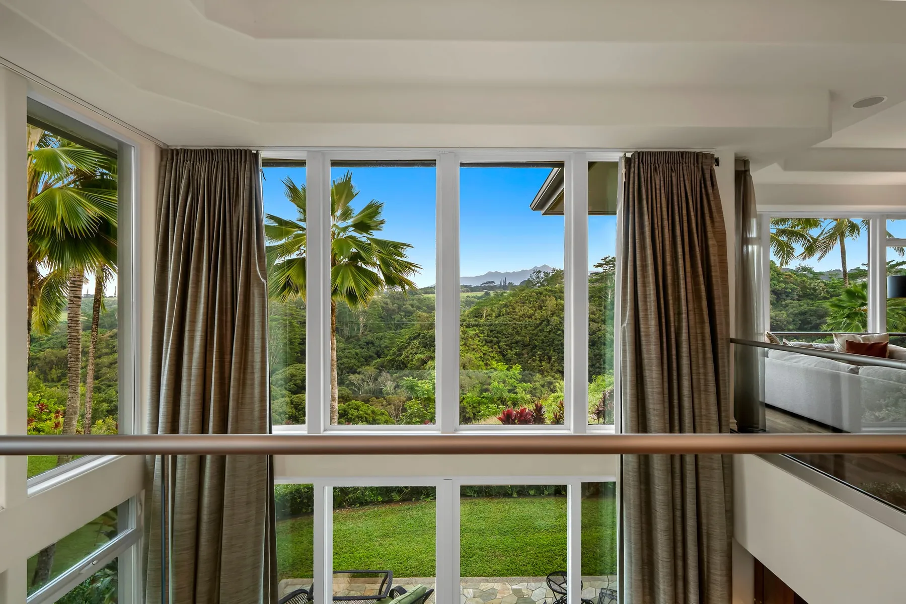 A bright interior overlooks green gardens and palm trees through tall windows.