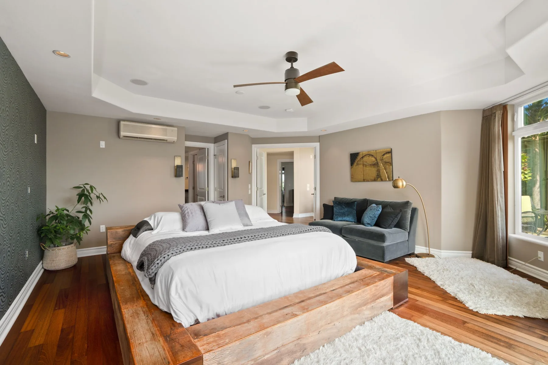 A bedroom with a large bed and a seating area beside the windows.