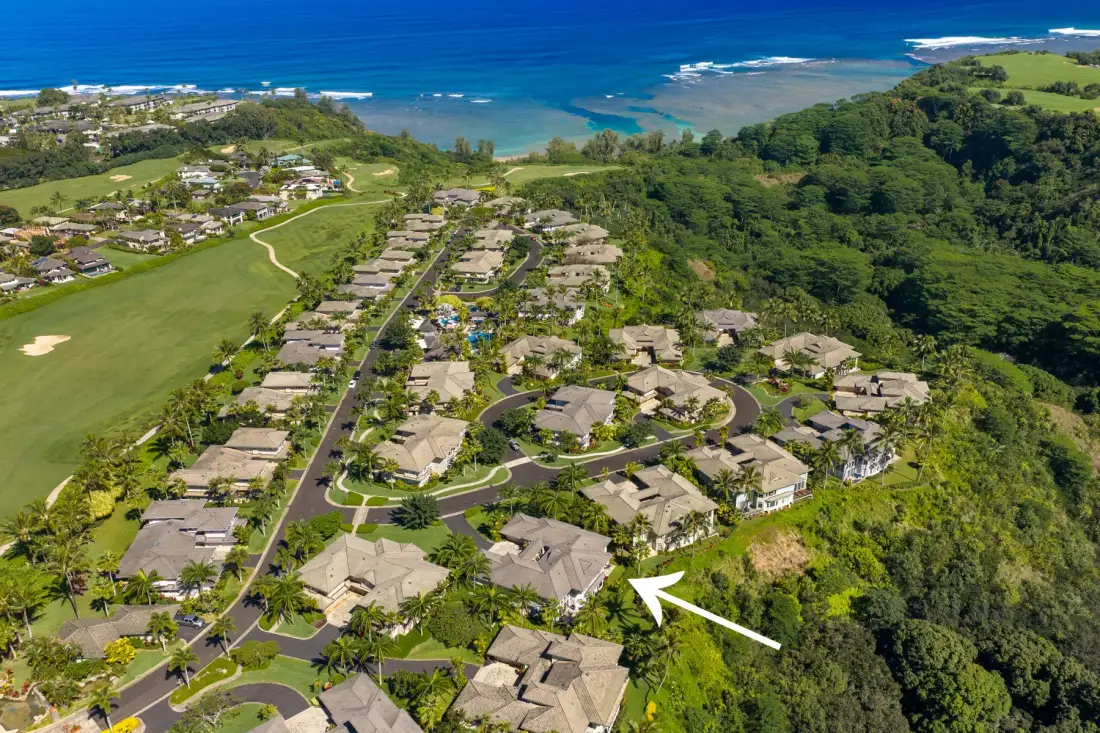 An aerial view of a coastal residential development surrounded by green hills.