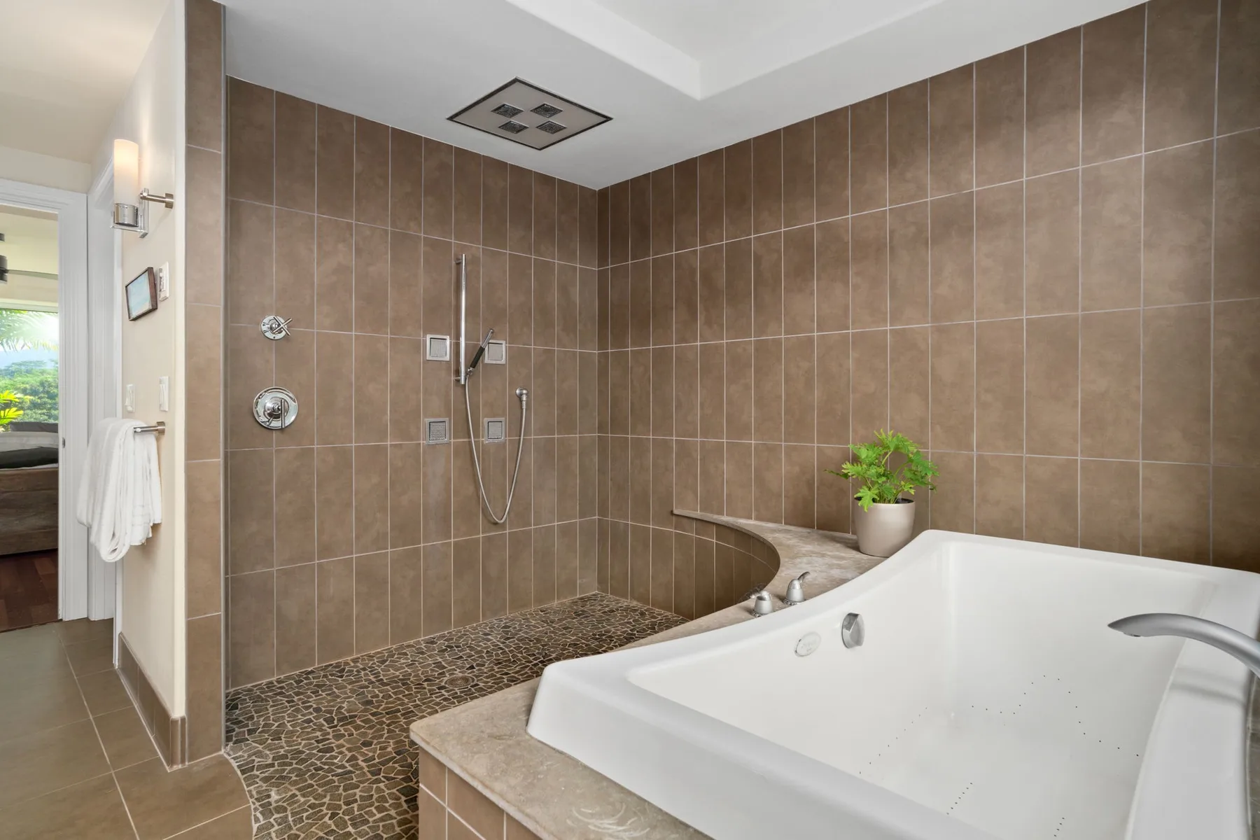 A tiled bathroom features a large bathtub beside a walk-in shower.