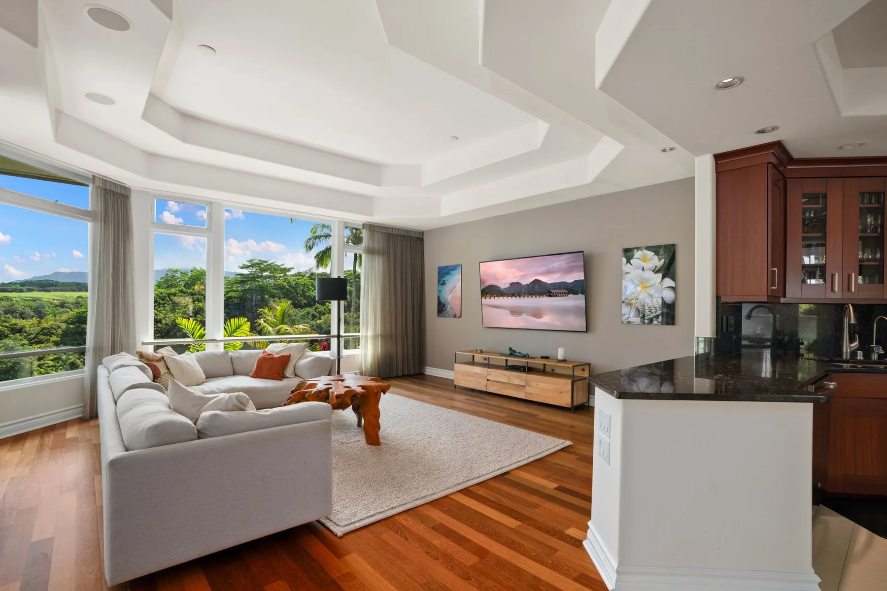 A bright living room with seating, large windows, and a kitchen counter.