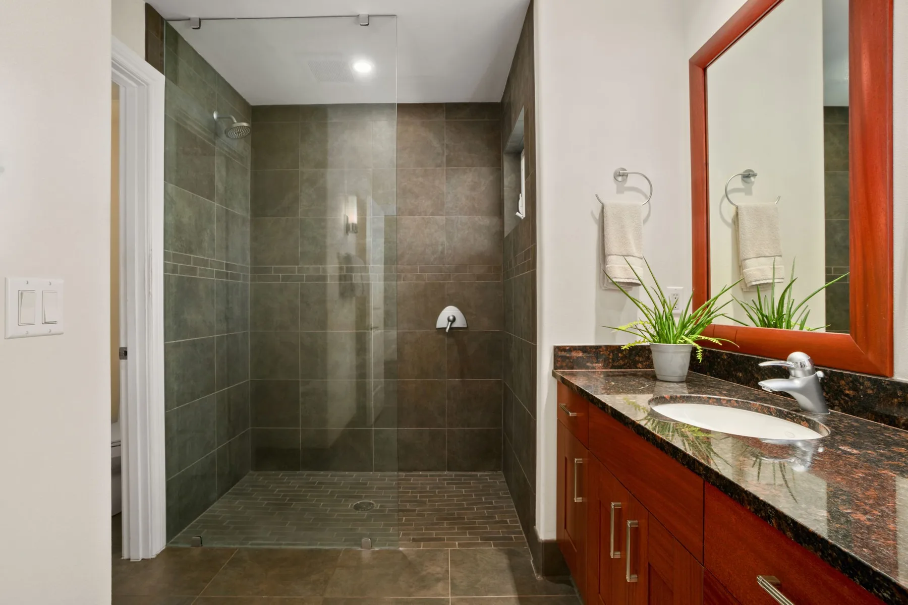 A tiled bathroom features a walk-in shower and a vanity with a sink.