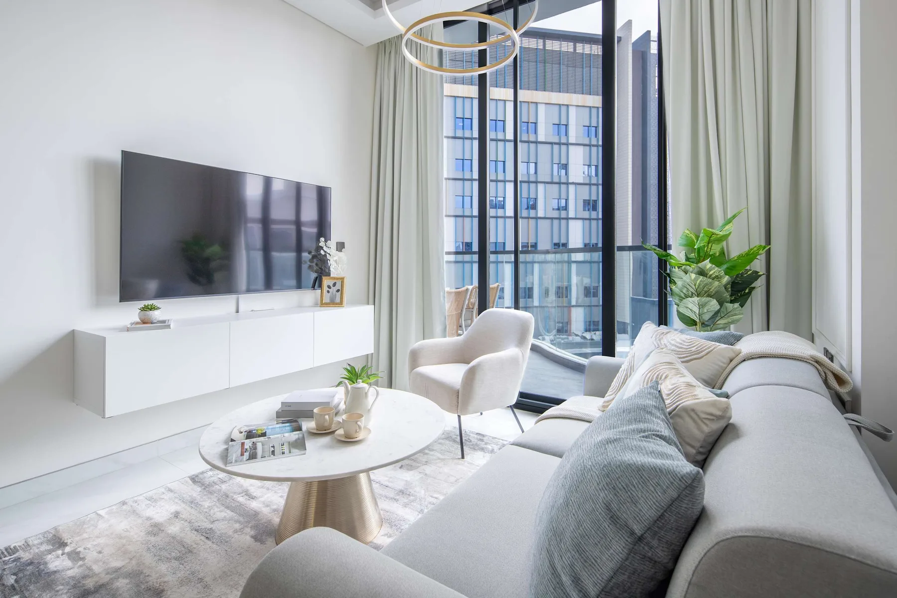A bright living room with seating, a television, and large windows.