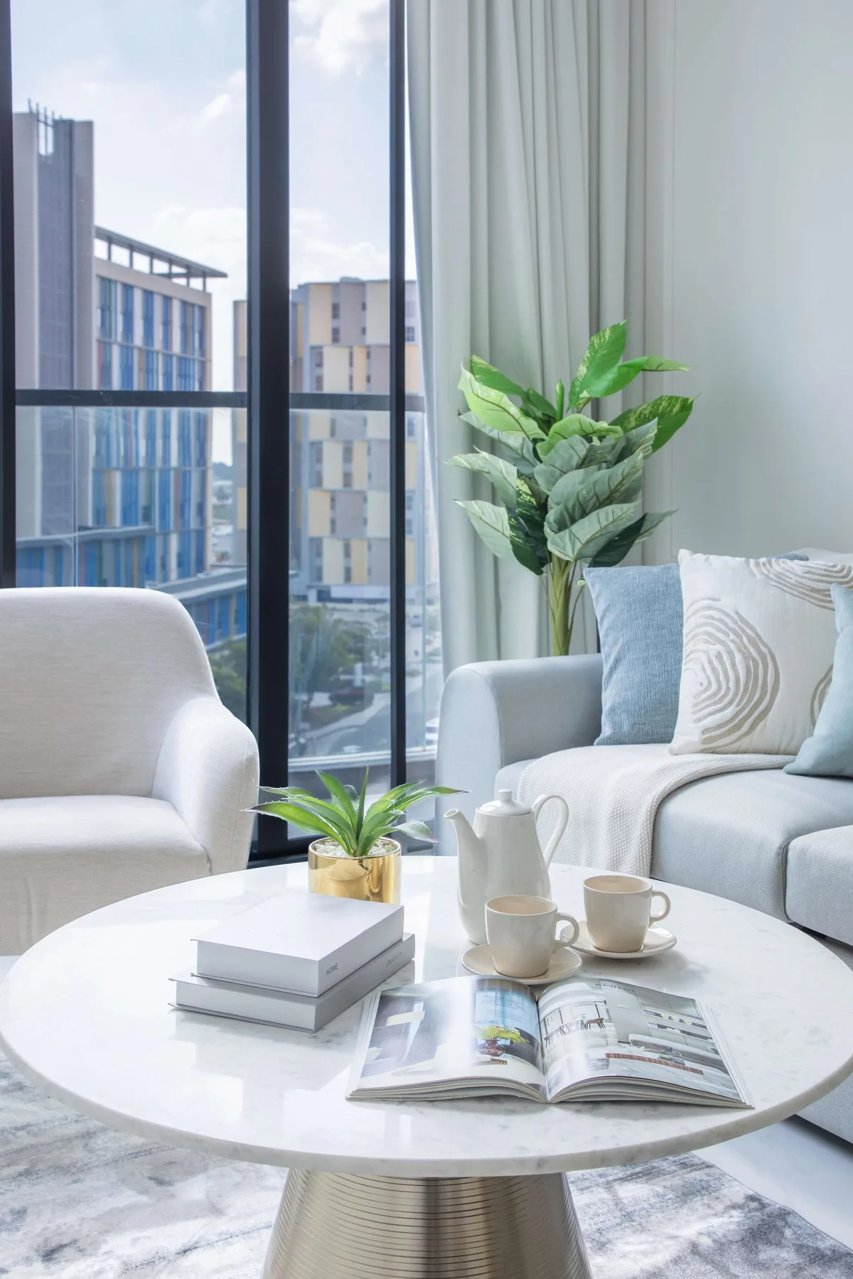 A bright living room with seating around a coffee table beside large windows.