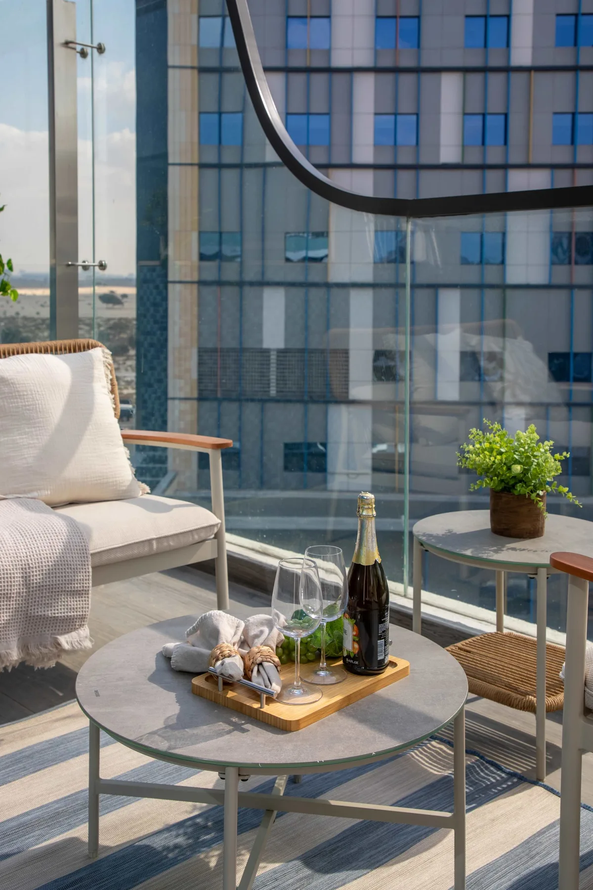 A balcony seating area with a round table and a potted plant.
