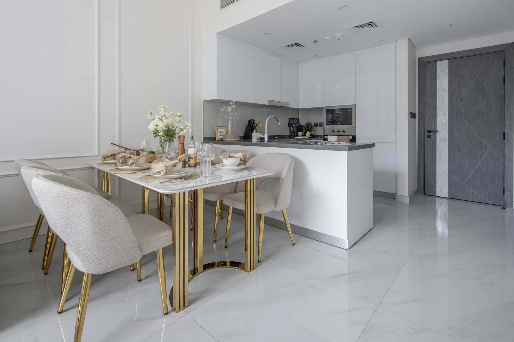 A bright dining area with a set table beside an open kitchen.
