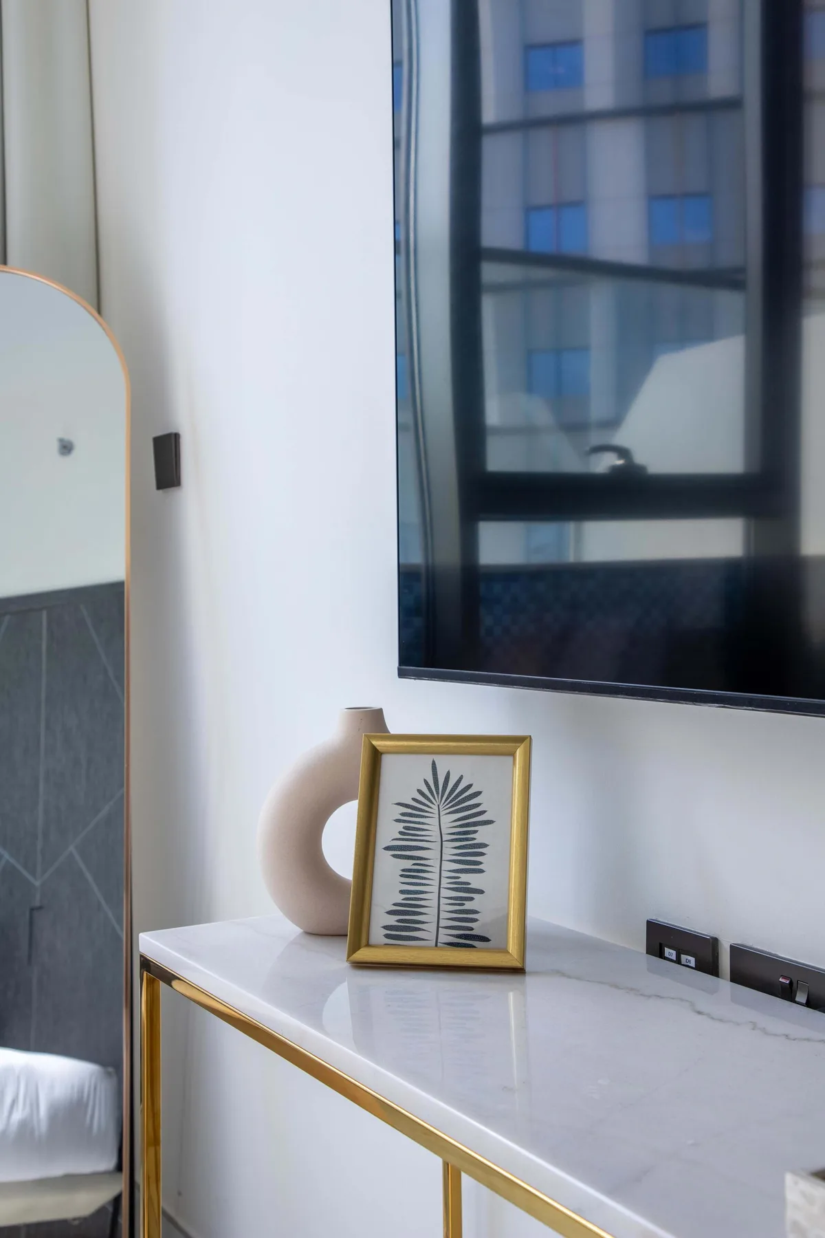 A bedroom vanity with a framed botanical print beneath a wall-mounted television.