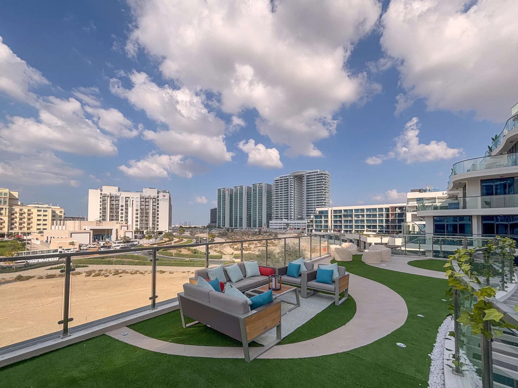 A rooftop terrace with outdoor seating overlooks nearby buildings beneath a cloudy sky.