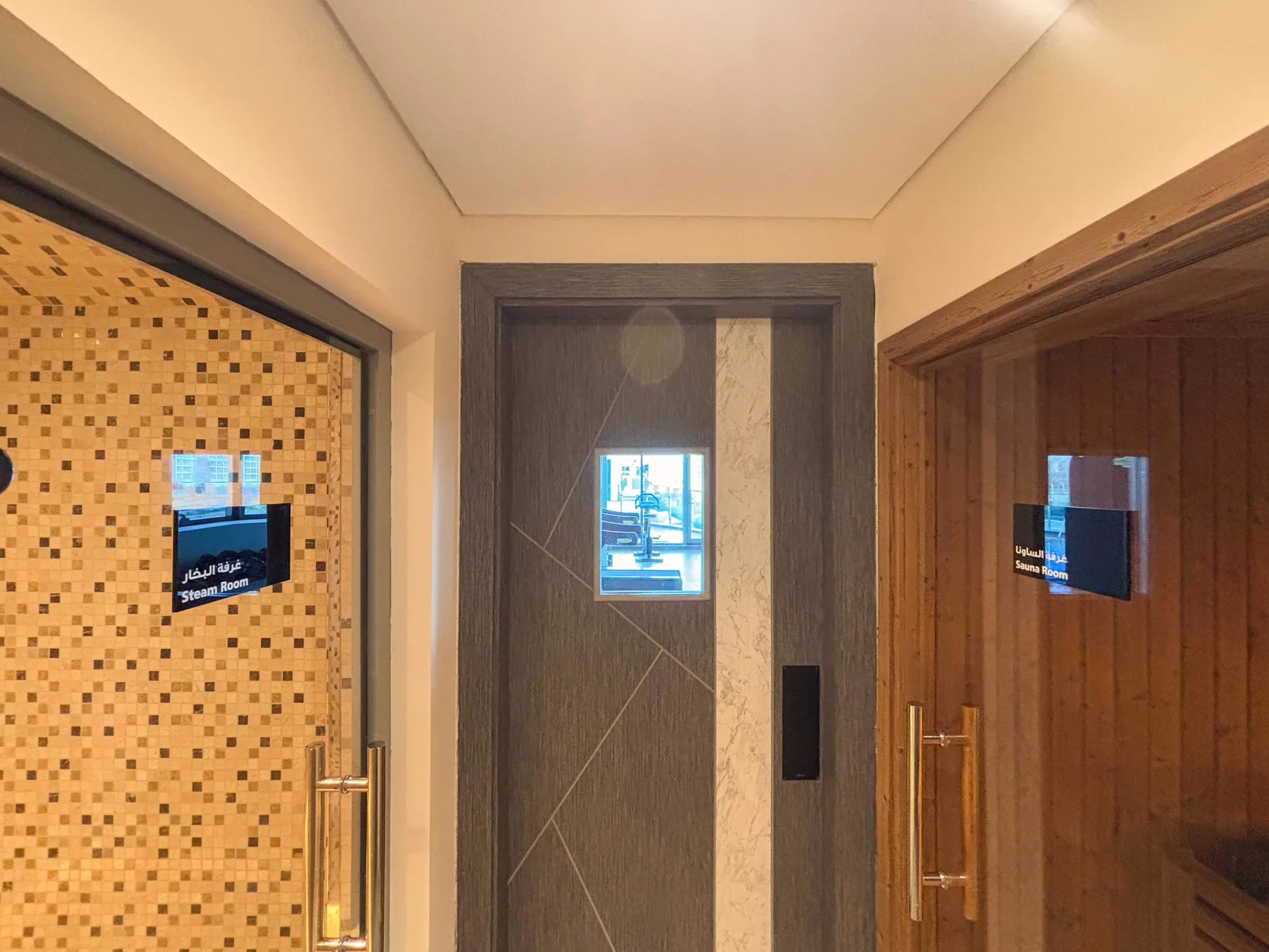 An elevator lobby with dark wood doors and illuminated display panels.