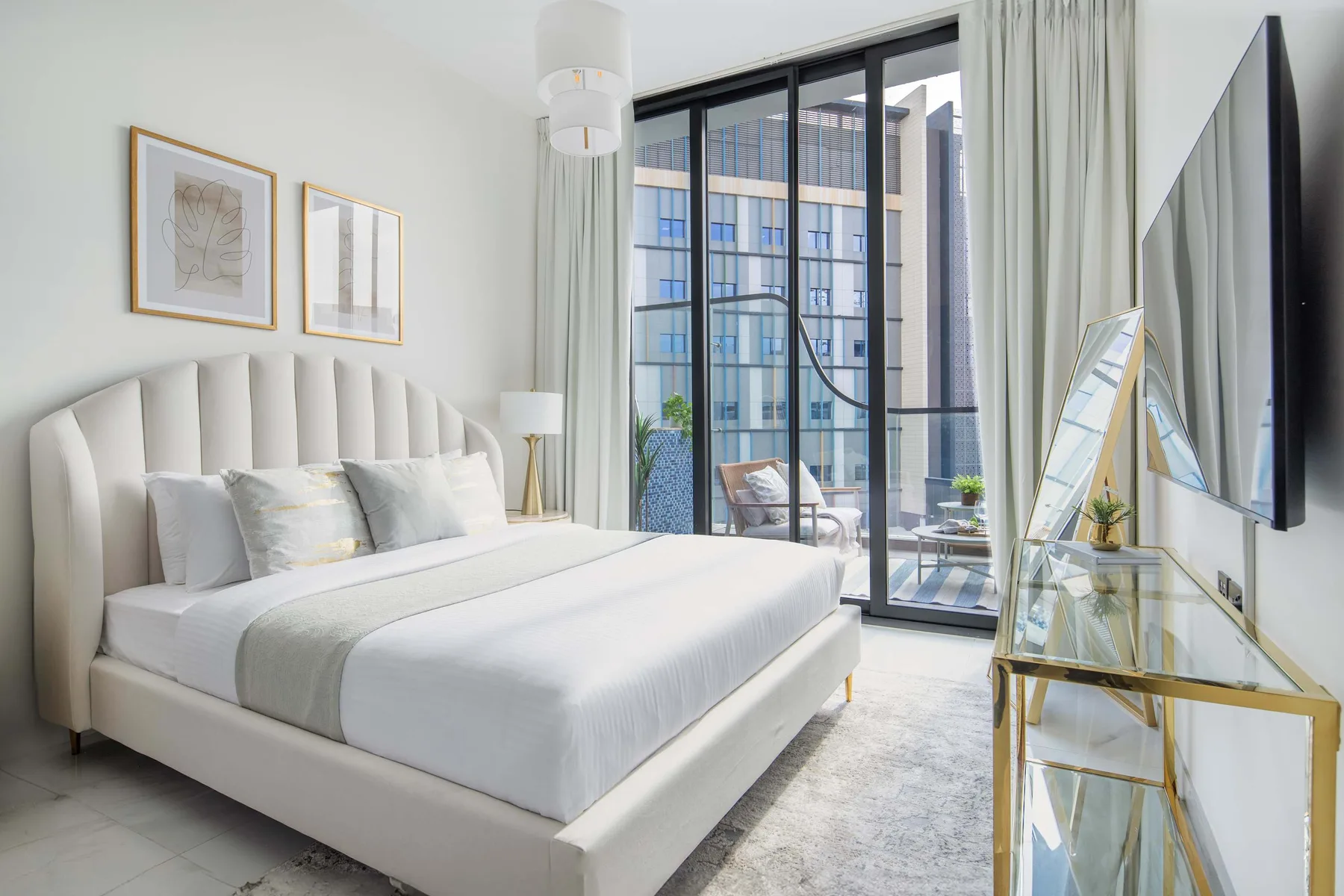 A bright bedroom with a large bed beside floor-to-ceiling windows.