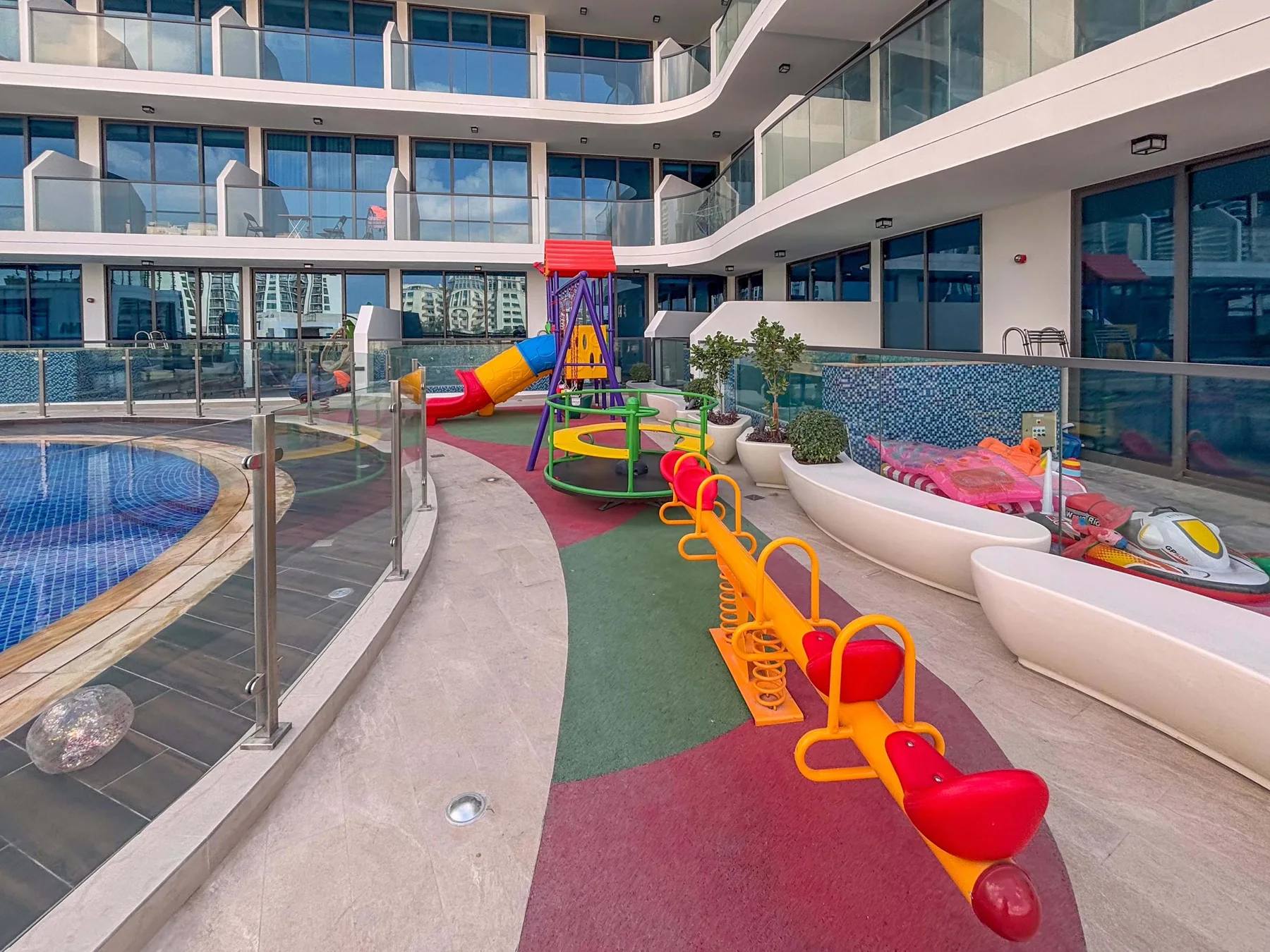 An outdoor pool area with a colorful playground beside it.