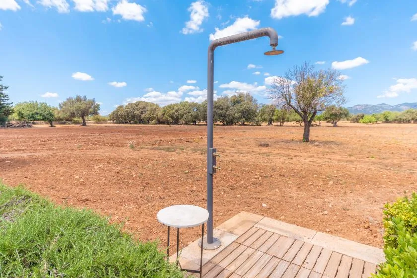 Una ducha exterior está junto a una plataforma de madera con vistas a un paisaje seco y abierto.