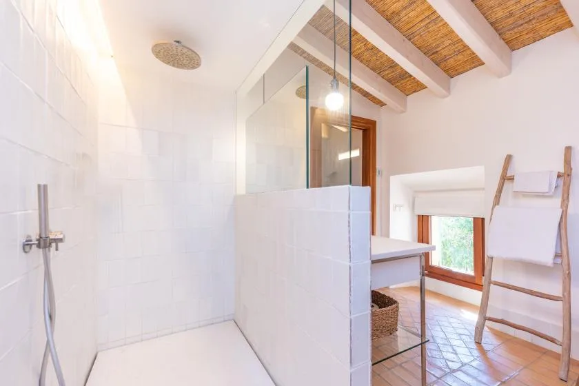 Un baño luminoso con ducha y techo de madera.
