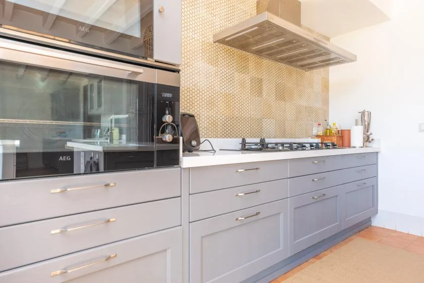 Una cocina moderna con gabinetes grises, una placa de cocina y una campana extractora.