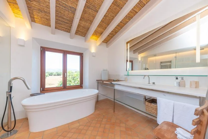 Un baño luminoso con bañera exenta, un lavabo largo y un espejo grande.