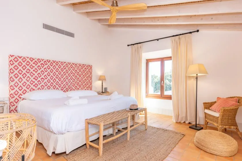 Un dormitorio luminoso con una cama grande, un cabecero estampado y una ventana.