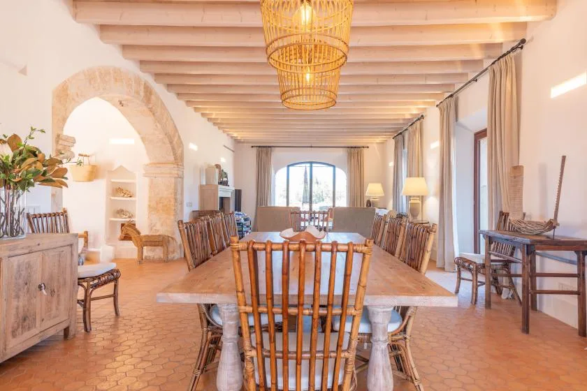 Un comedor con una larga mesa de madera bajo vigas expuestas.